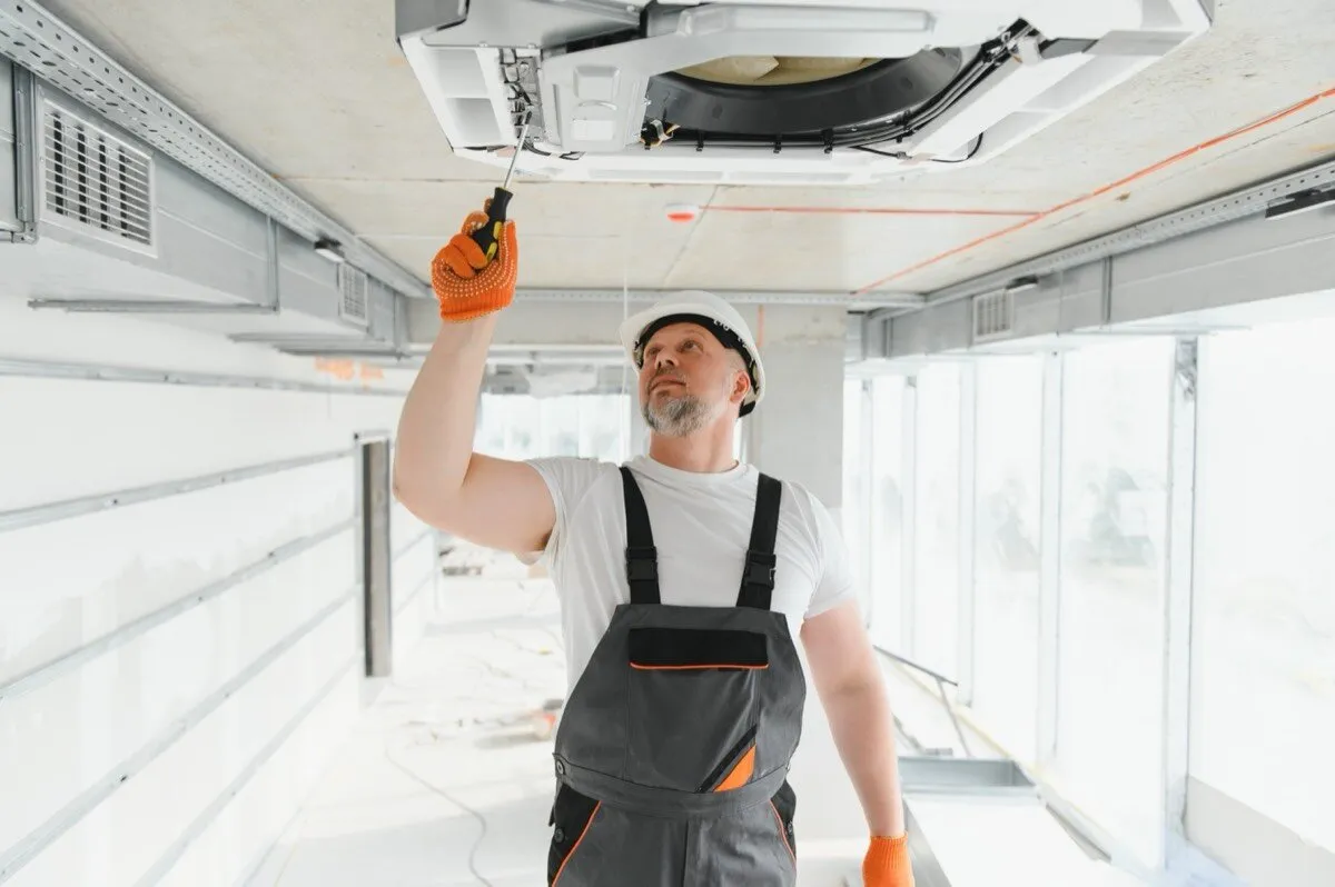 Technician installing a ceiling cassette AC unit